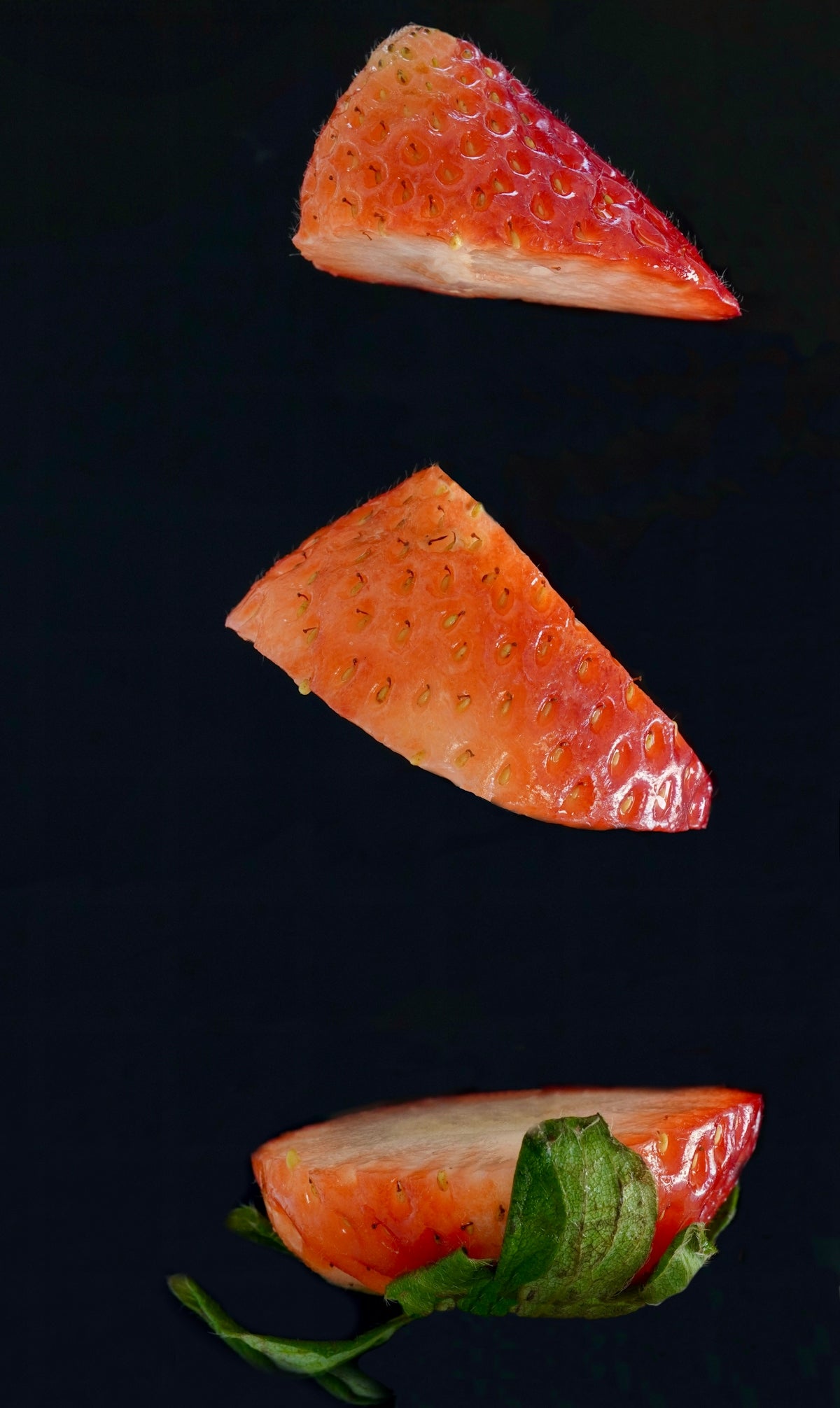 A piece of salmon and a piece of lettuce on a black surface