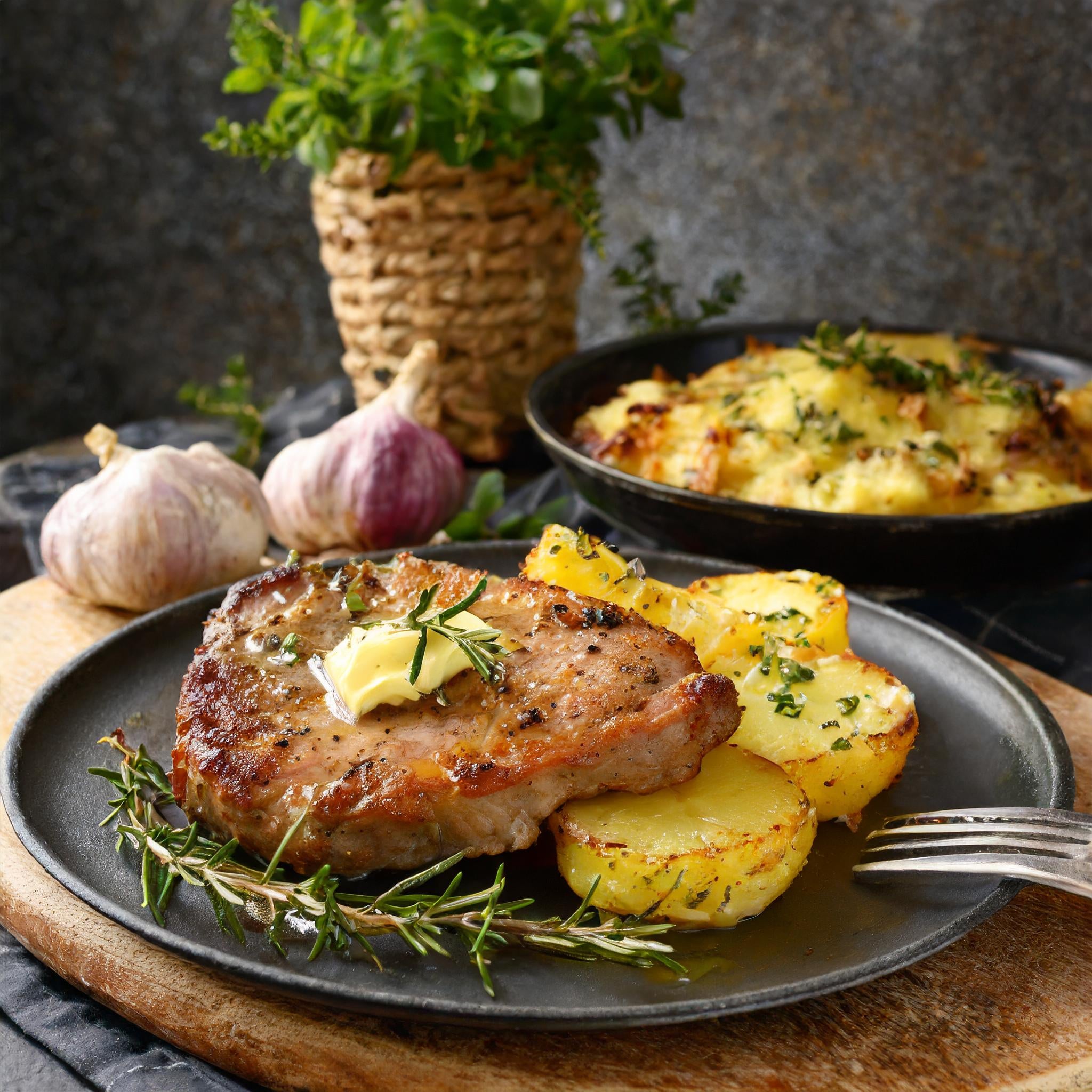 Gebratene Schweinesteaks mit Kräuterbutter und Kartoffelgratin Gebratene Schweinesteaks mit Kräuterbutter und Kartoffelgratin